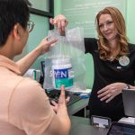 SYNC employee completing transaction with customer buying collagen supplement, Boost the Health & Productivity of Your Employees with SYNC Life's Executive Wellness Program