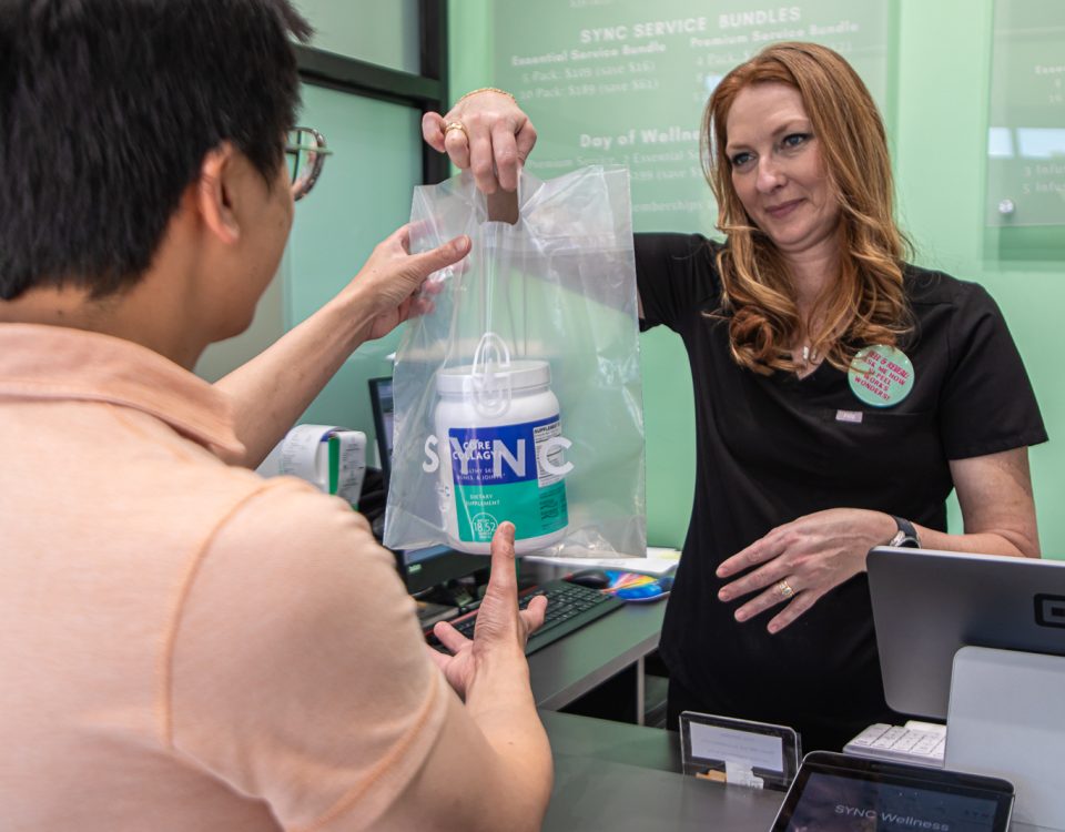 SYNC employee completing transaction with customer buying collagen supplement, Boost the Health & Productivity of Your Employees with SYNC Life's Executive Wellness Program