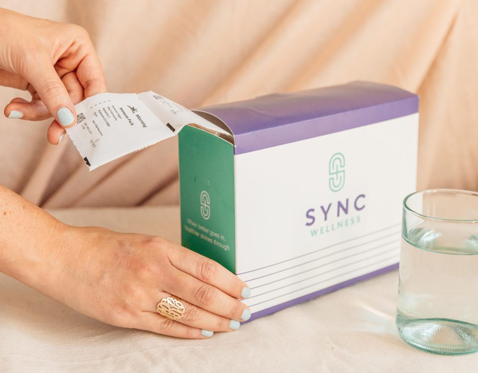 box of personalized sync packs with hands and glass of water, 5 Advantages of Professional-Grade Nutritional Supplementation