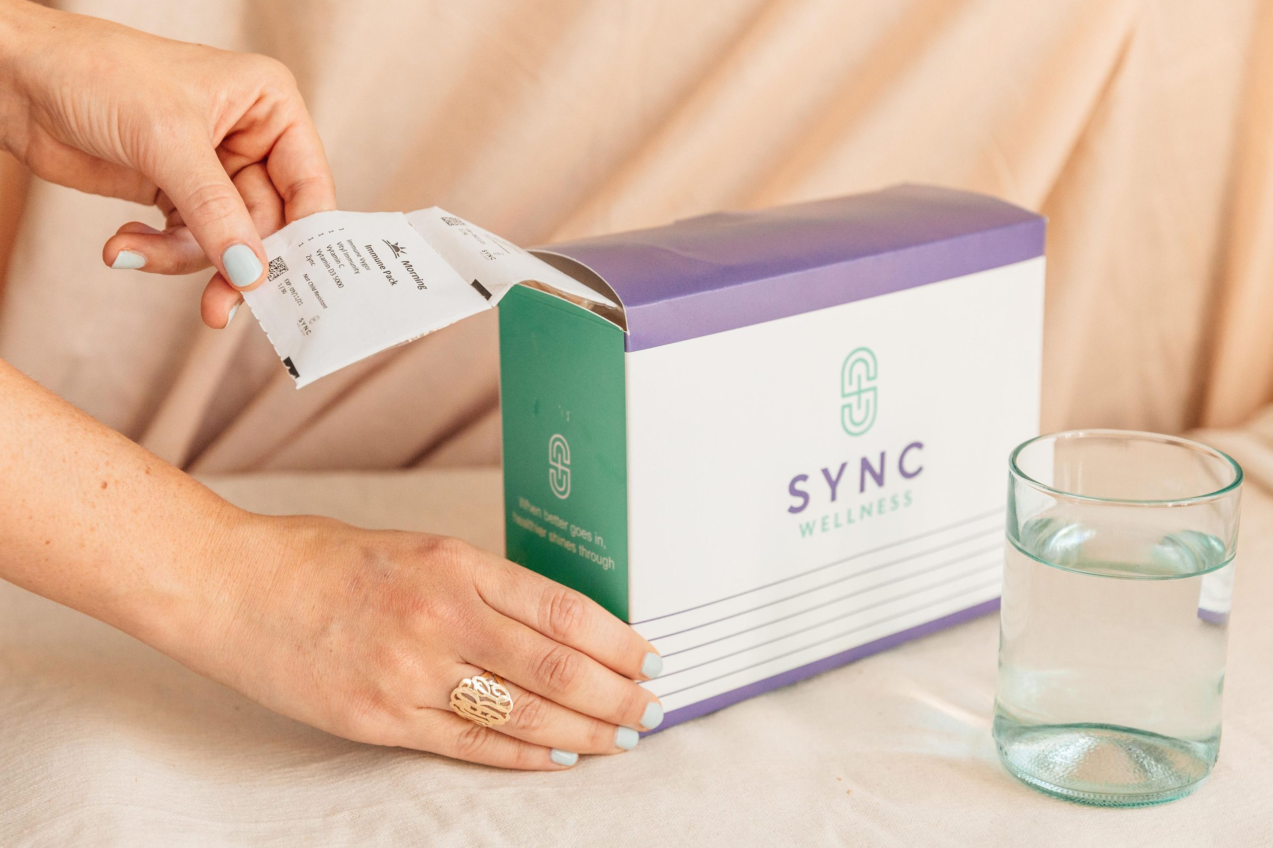 box of personalized sync packs with hands and glass of water, 5 Advantages of Professional-Grade Nutritional Supplementation